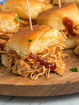 slow cooker bbq chicken sliders on a wooden serving tray.