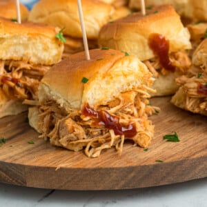 slow cooker bbq chicken sliders on a wooden serving tray.