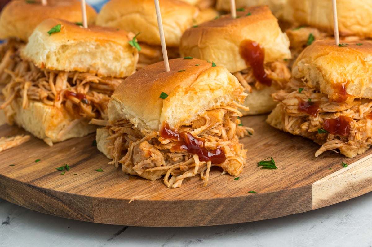 slow cooker bbq chicken sliders on a wooden serving tray.