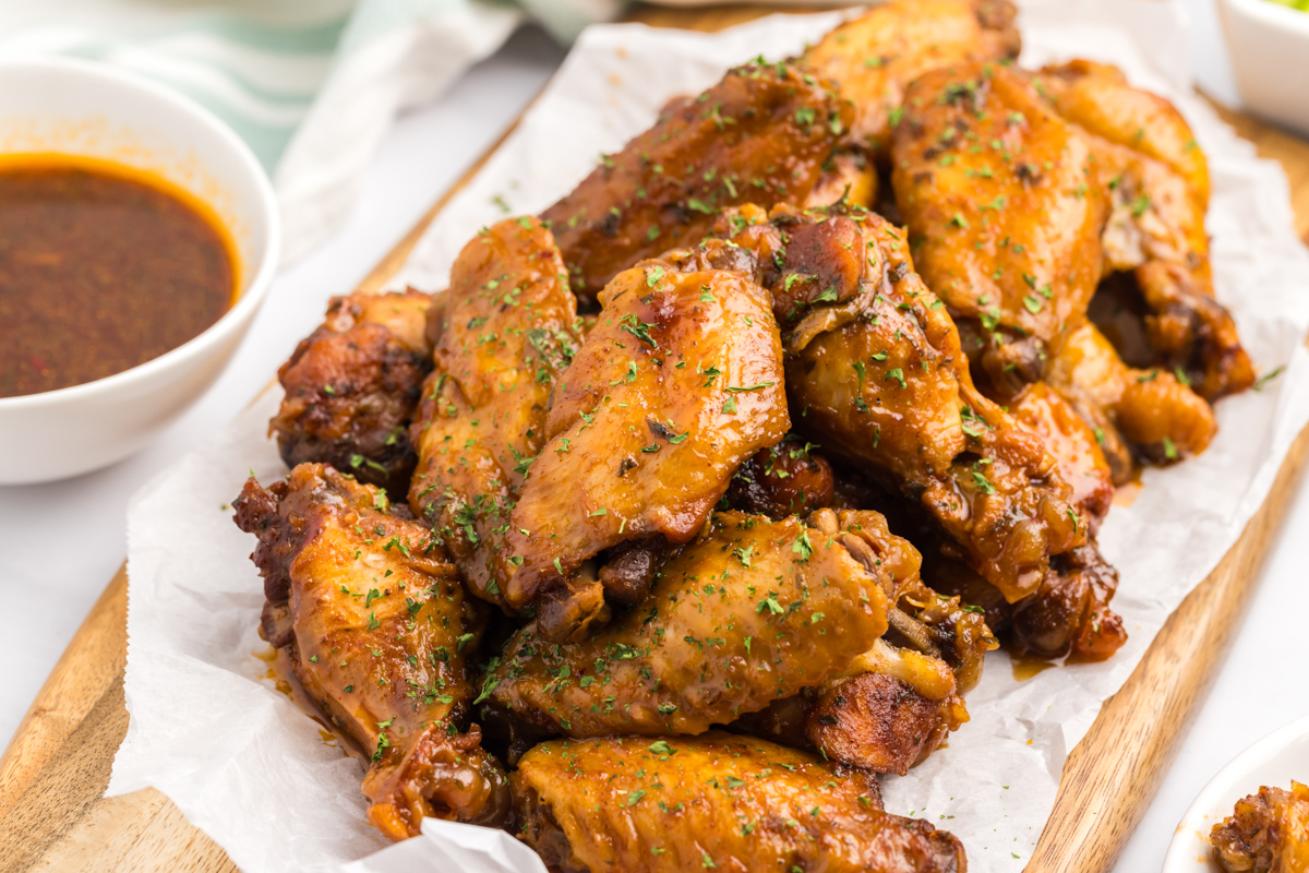 slow cooker bbq chicken wings on a wooden serving block.