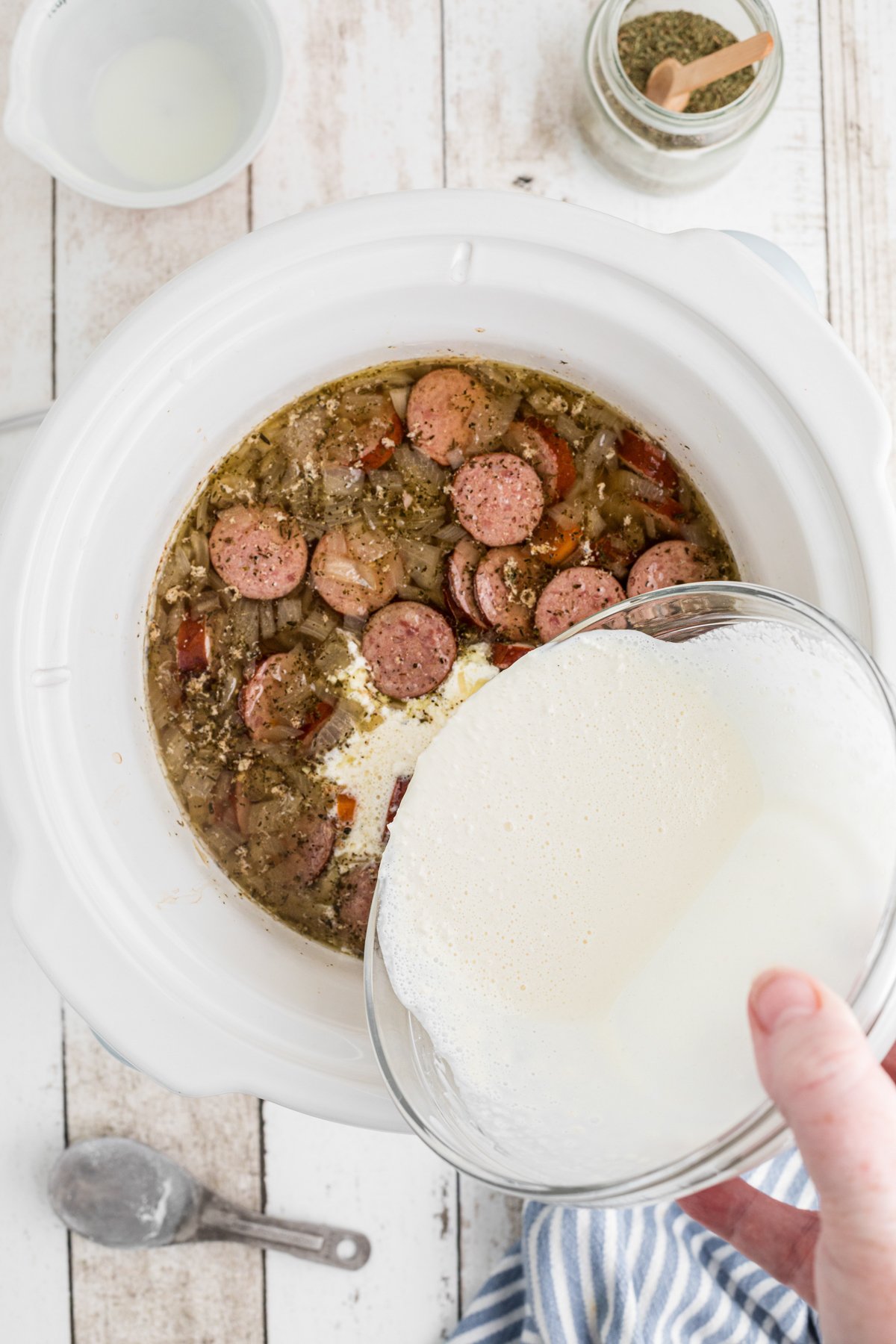 cream mixed with flour being poured into kielbasa soup.