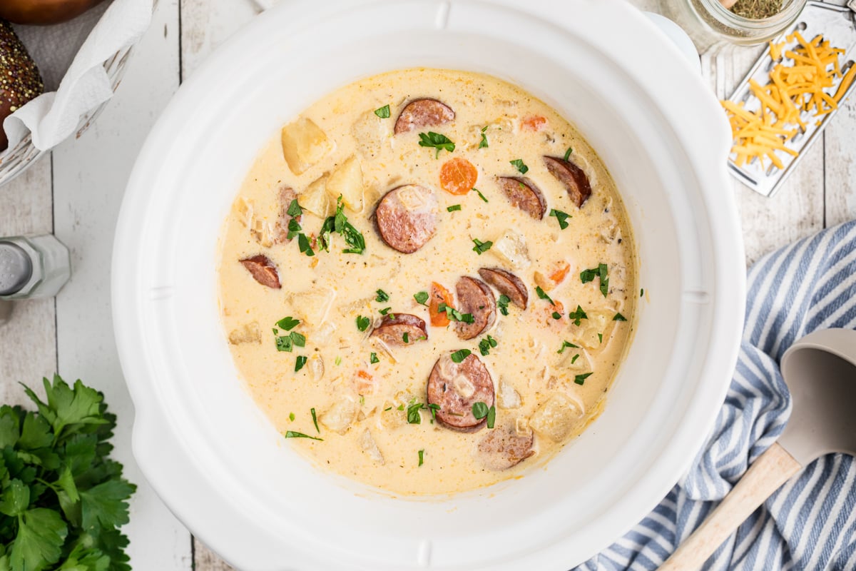 overhead of cheesy kielbasa soup in a slow cooker.