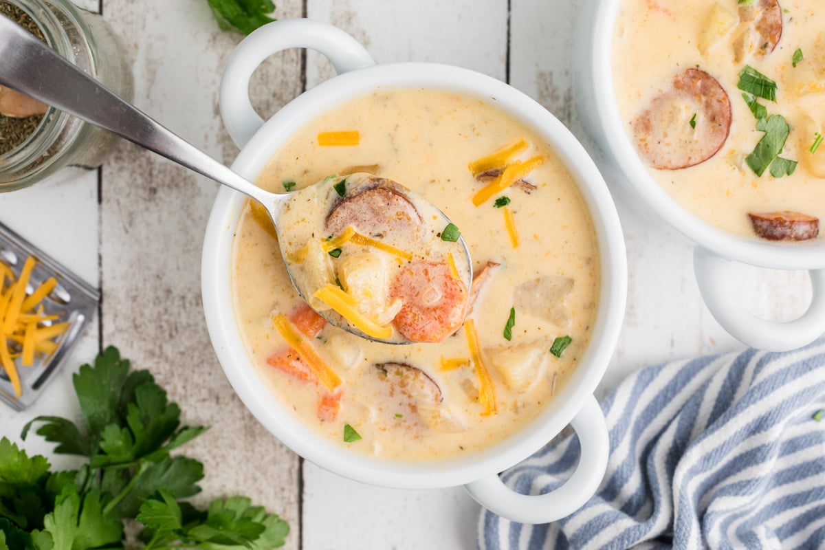 overhead shot of slow cooker cheesy kielbasa soup in a bowl with a spoon.