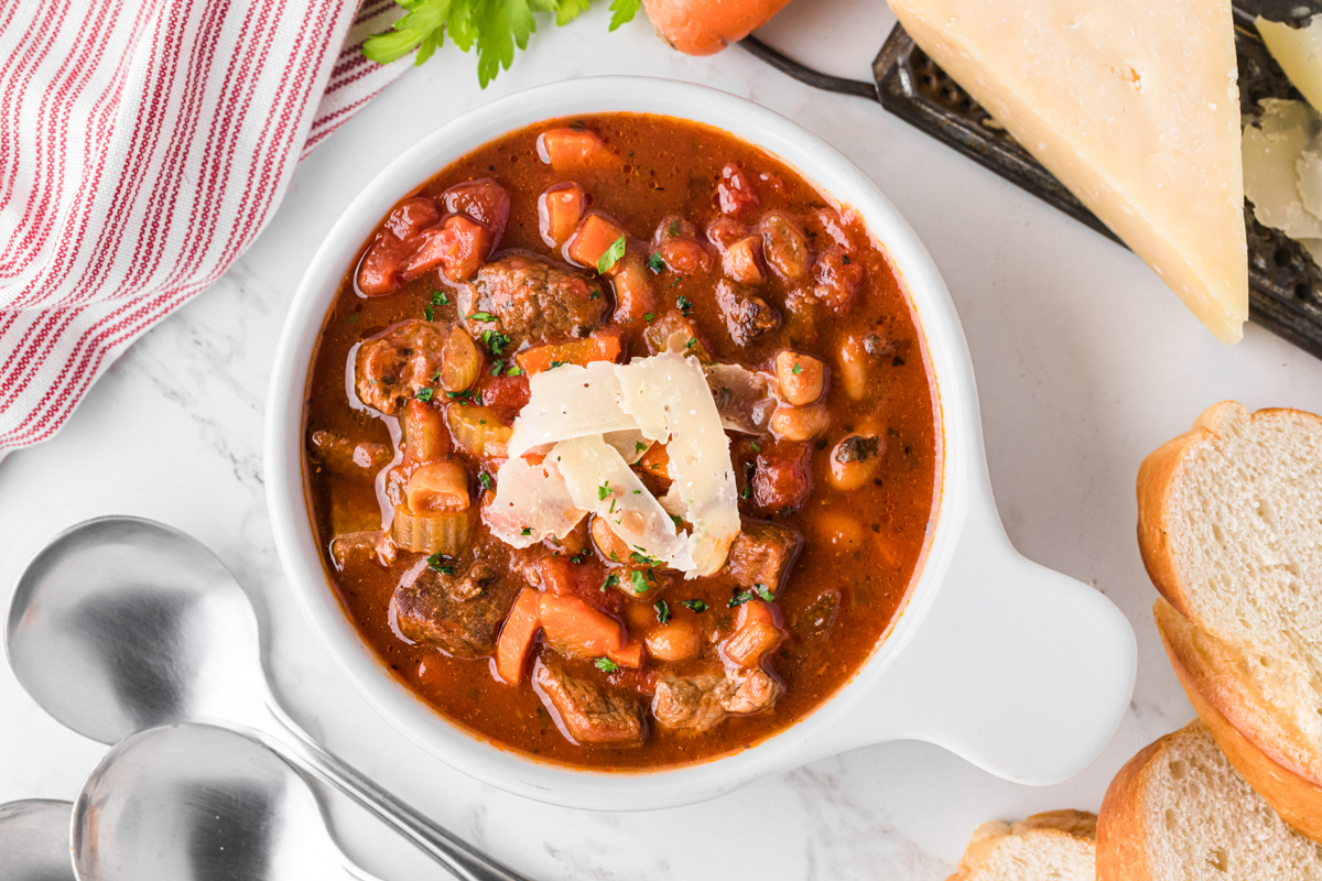 overhead of slow cooker hearty italian beef soup in a white bowl. 