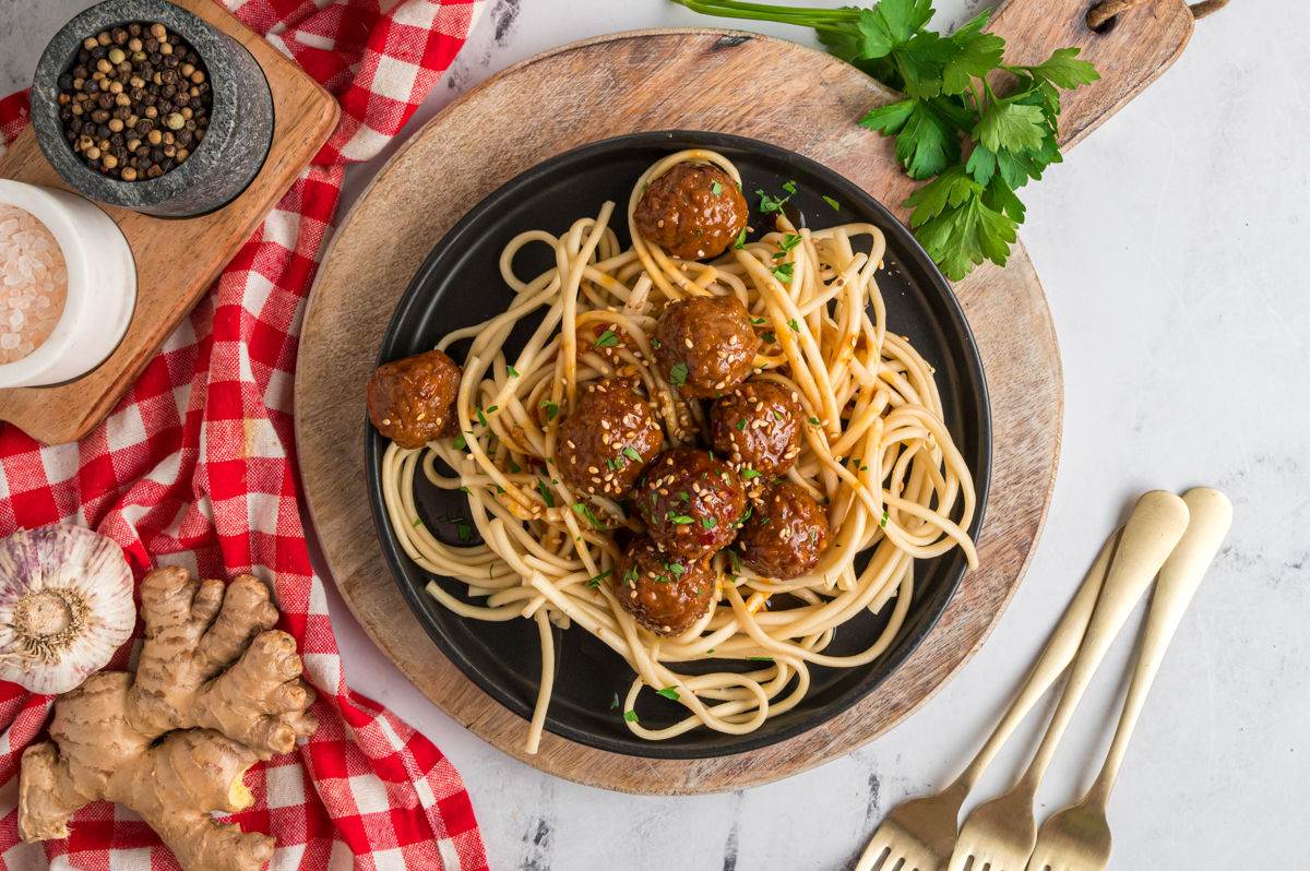 overhead of serving of slow cooker honey garlic meatballs on noodles.