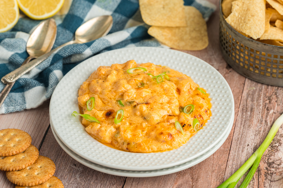 serving of slow cooker hot shrimp dip on a stack of plates.