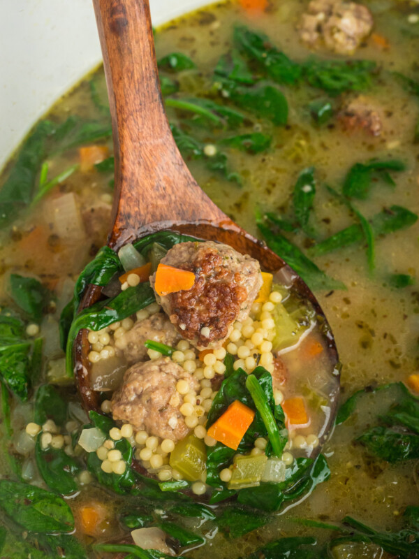 spoon scooping out some italian wedding soup from a slow cooker.