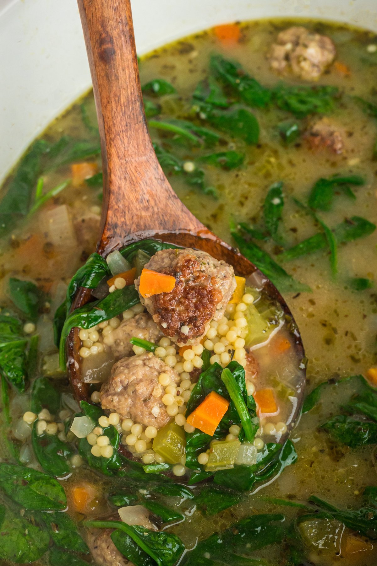 spoon scooping out some italian wedding soup from a slow cooker.