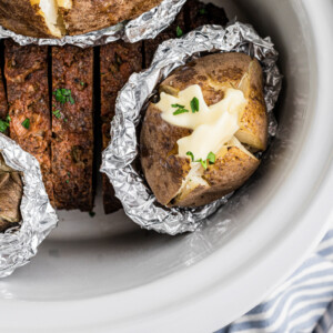 overhead of slow cooker meatloaf and baked potatoes.