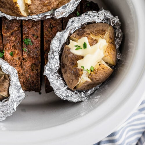 overhead of slow cooker meatloaf and baked potatoes.