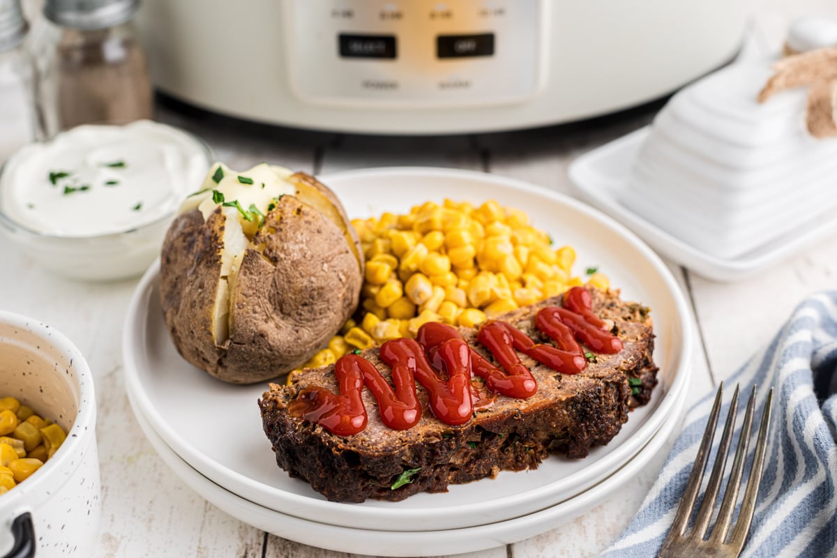 slow cooker meatloaf and baked potatoes on a plate.