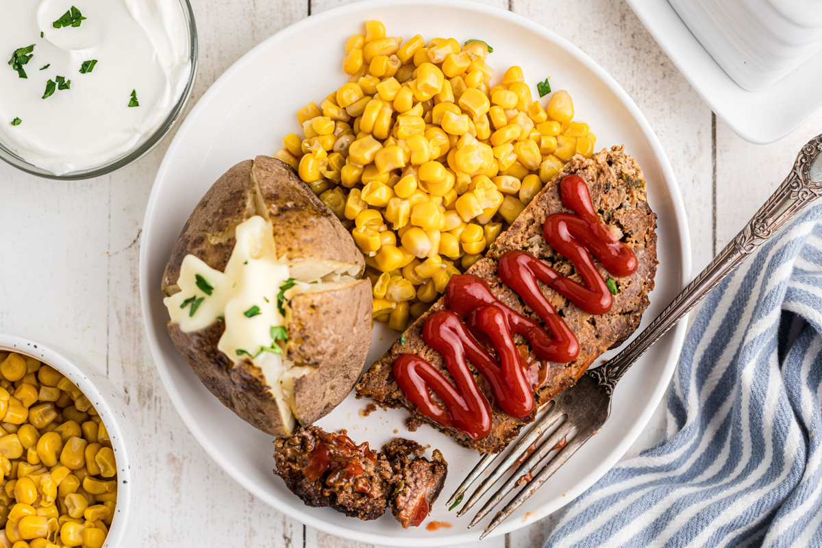 overhead of slow cooker meatloaf and baked potatoes on a plate.