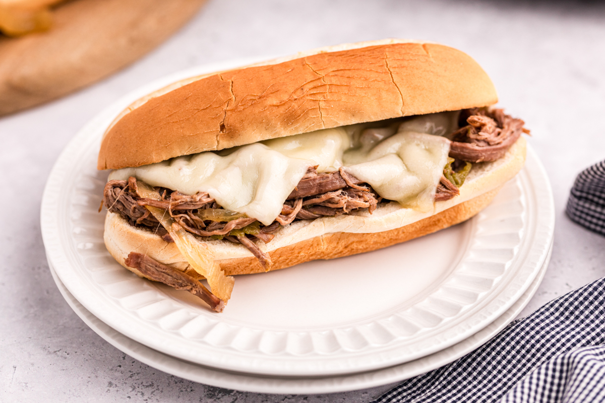 one slow cooker philly cheese steak on a stack of plates.