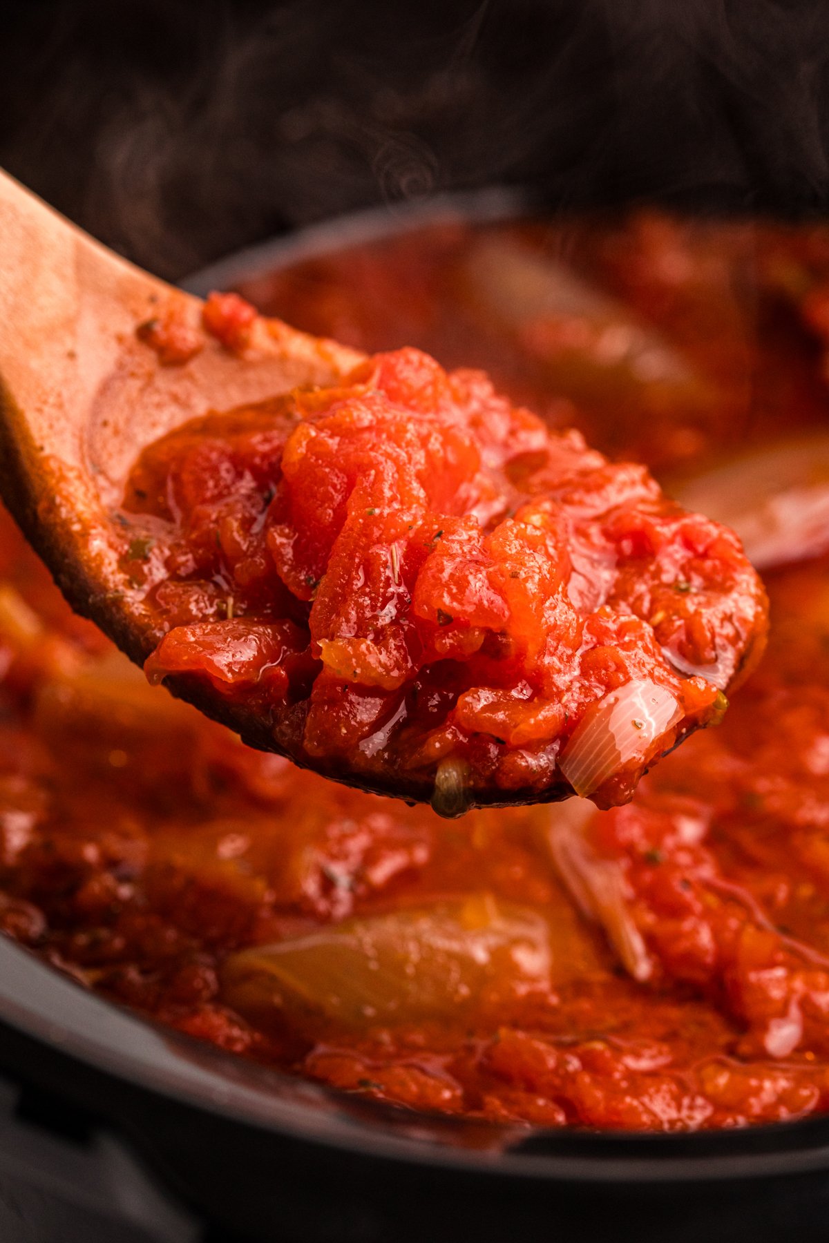 slow cooker tomato butter sauce on a wooden spoon.