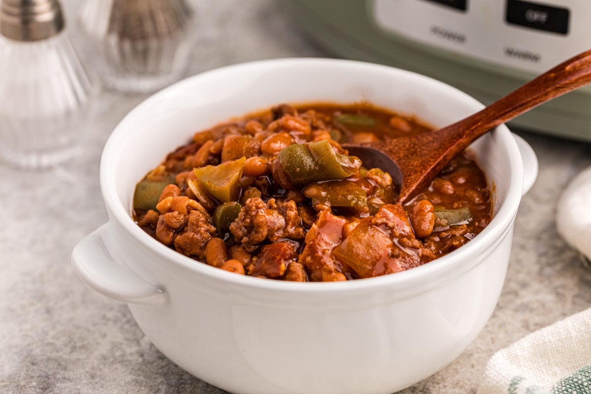 slow cooker land your man baked beans in a bowl with a spoon.