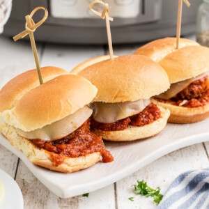 three slow cooker meatball sliders on a serving tray.