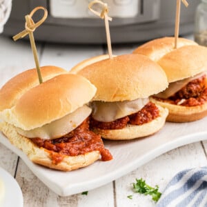 three slow cooker meatball sliders on a serving tray.