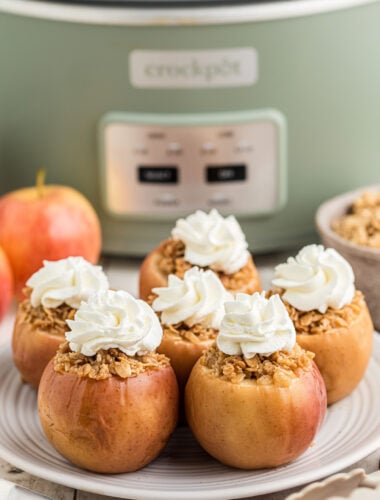 baked apples in front of a slow cooker with whipped cream.