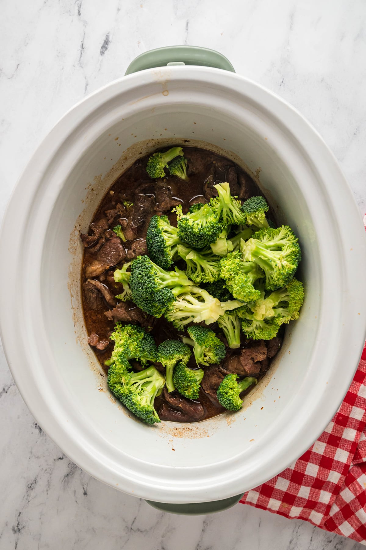 broccoli added to beef in a slow cooker.