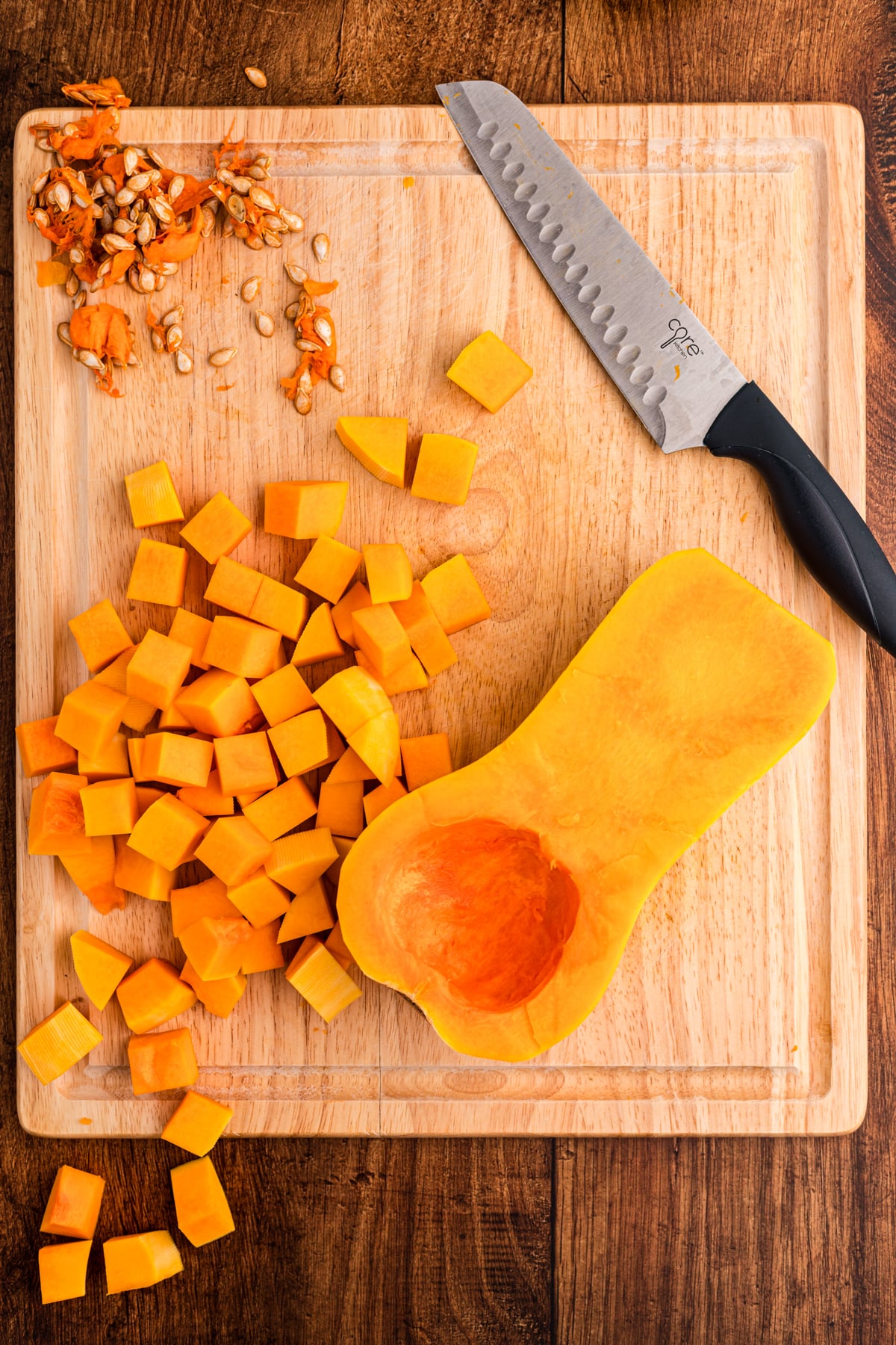 butternut squash being cut up on a cutting board.