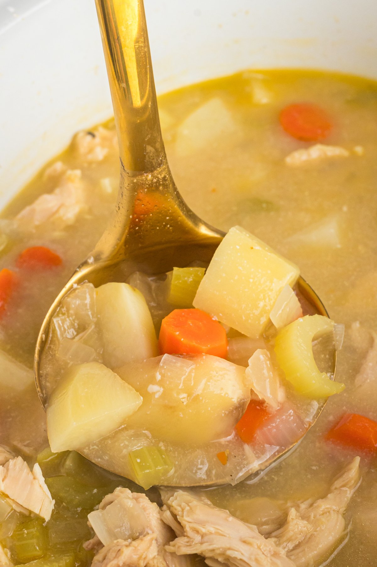 close up of crockpot chicken stew on a spoon.