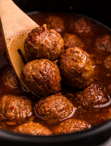 scooping jalapeno meatballs out of a slow cooker.