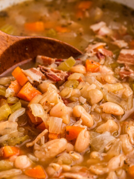 scooping out beer and bacon bean soup from a crockpot.