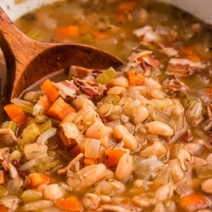 scooping out beer and bacon bean soup from a crockpot.