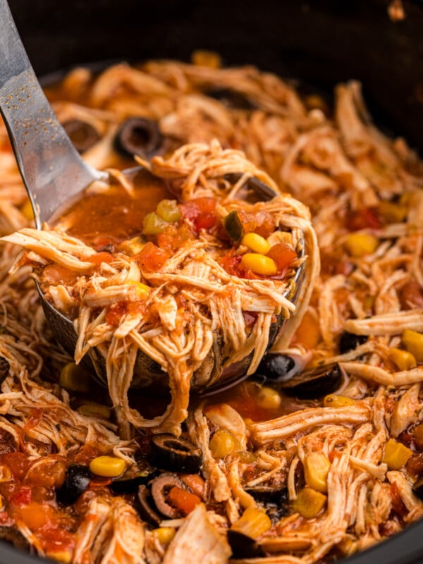 scooping out some crockpot chicken taco soup with a ladle.