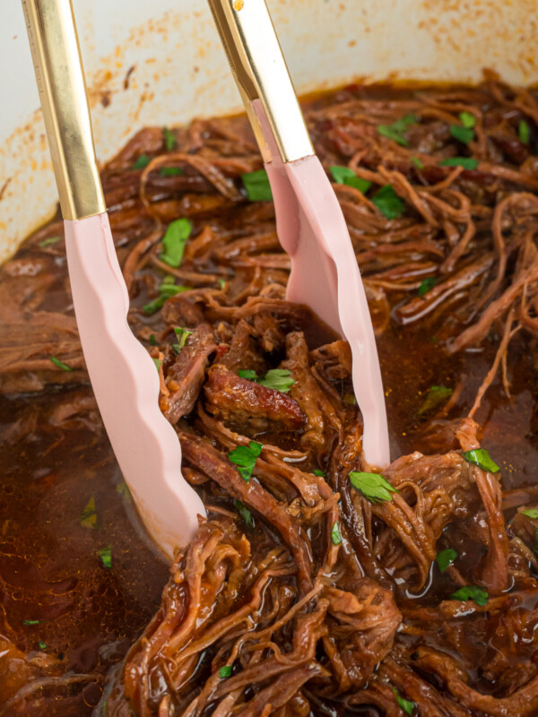 tongs taking out some crockpot flank steak.