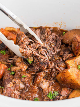 tongs grabbing some slow cooker italian beef dinner.