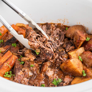 tongs grabbing some slow cooker italian beef dinner.