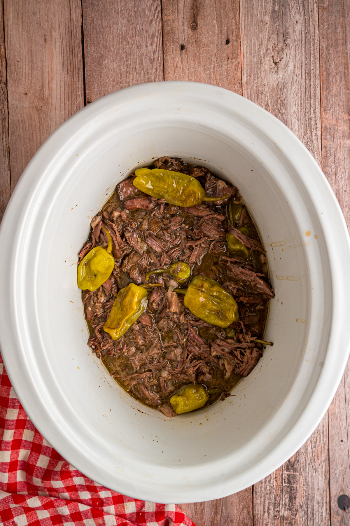 Mississippi pot roast in a slow cooker with peppers in it.