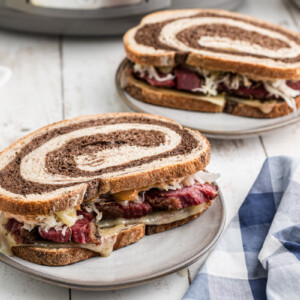two slow cooker pastrami sandwiches on plates.
