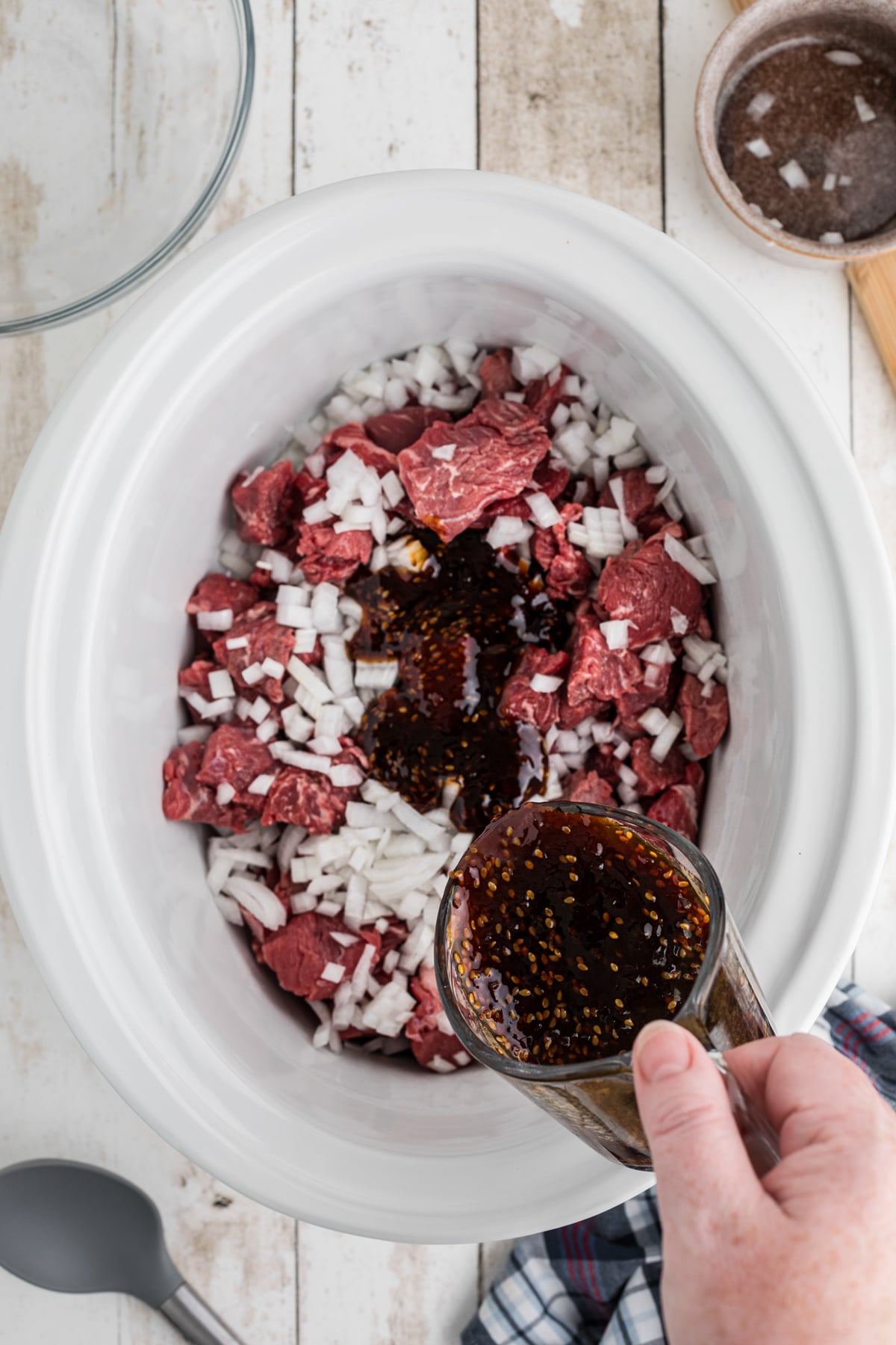 teriyaki sauce being poured over beef and onion.