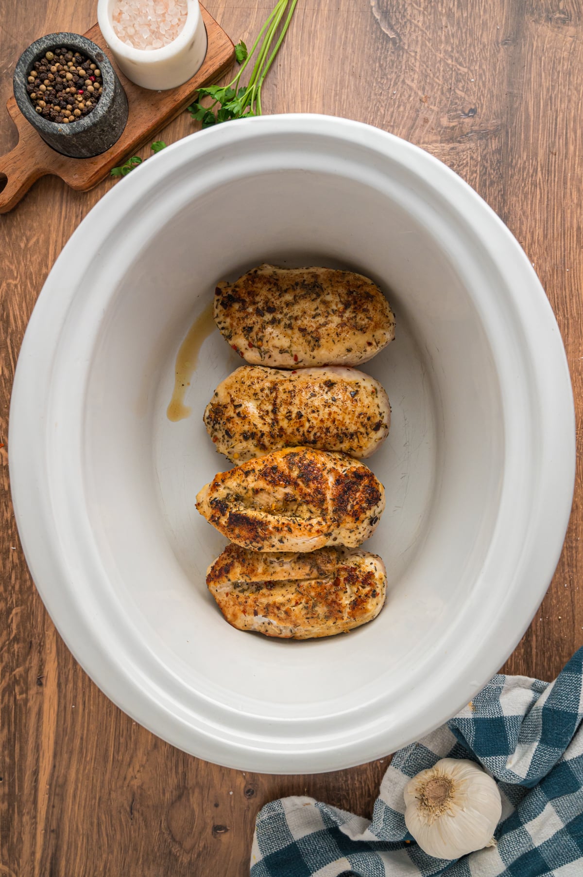 Chicken breasts in a slow cooker with seasonings.