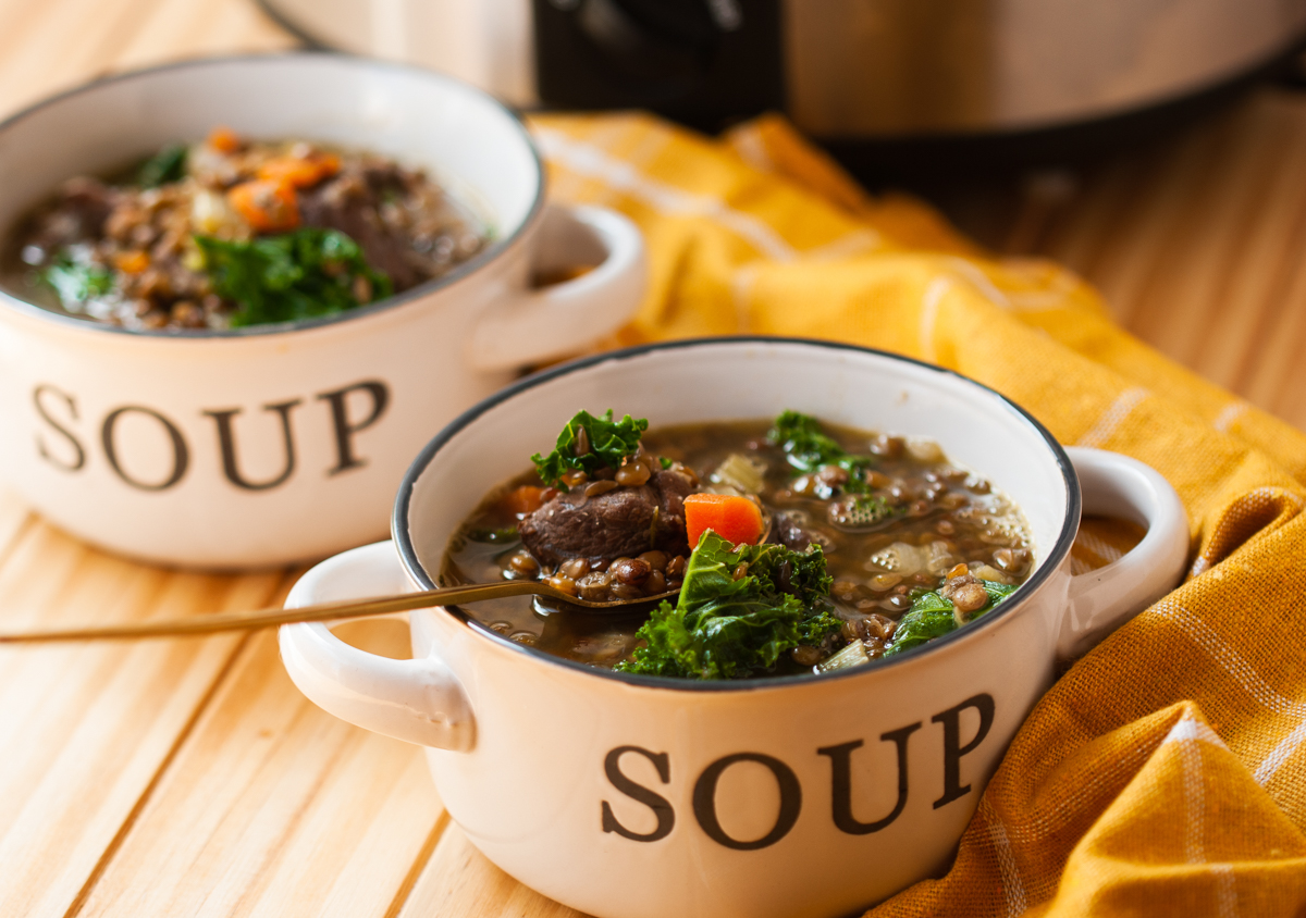 slow cooker beef and lentil soup in two bowls.