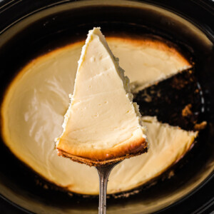 piece of cheesecake being held over a crockpot.