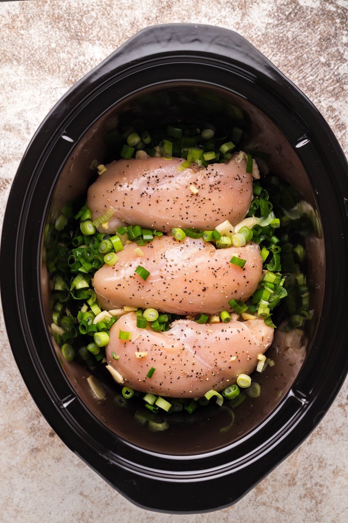 chicken breasts and green onions in a slow cooker.