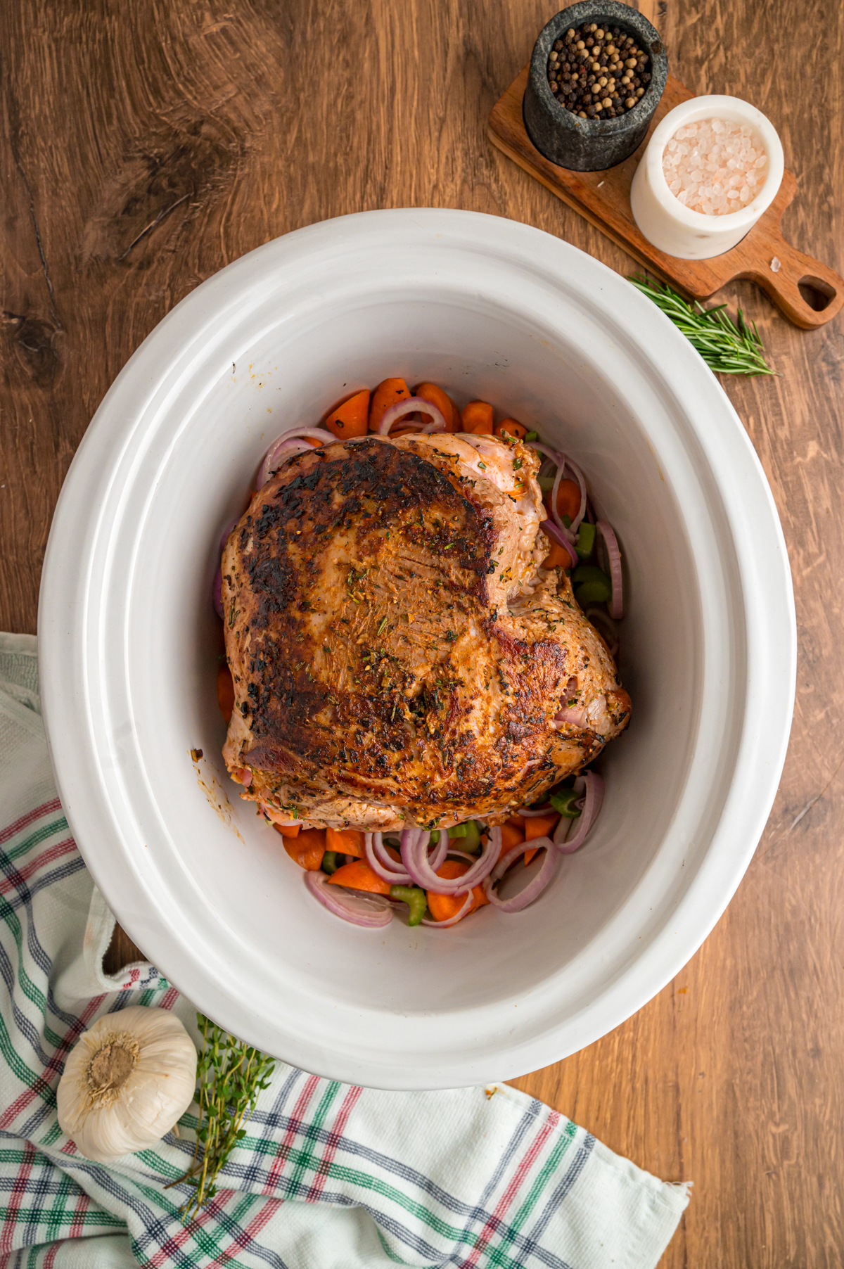 herb leg of lamb in a slow cooker over veggies.