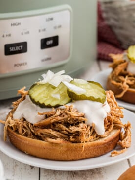 slow cooker nashville hot chicken sandwiches on buns with tops off.