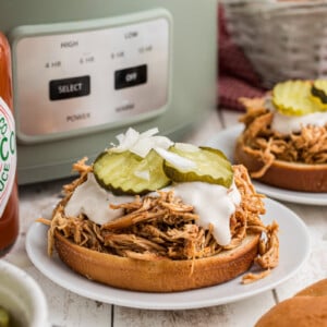 slow cooker nashville hot chicken sandwiches on buns with tops off.