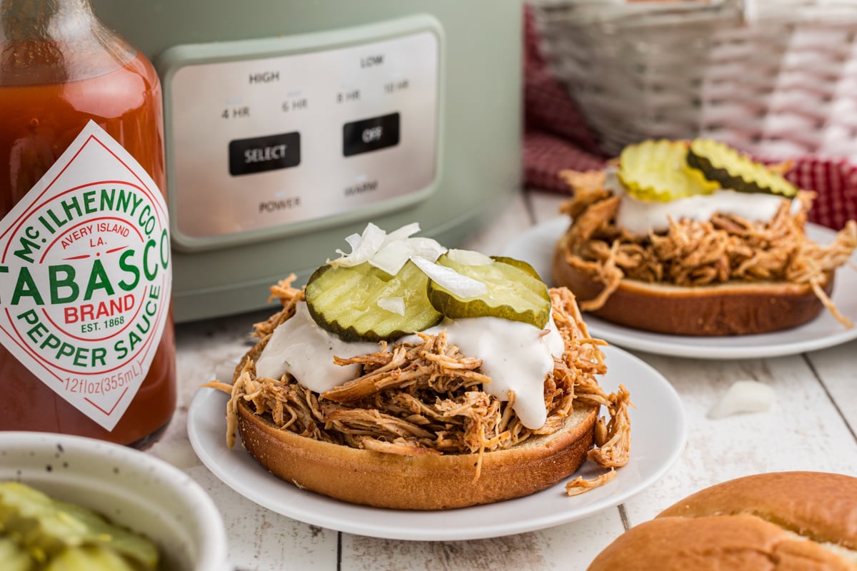 slow cooker nashville hot chicken sandwiches on buns with tops off.