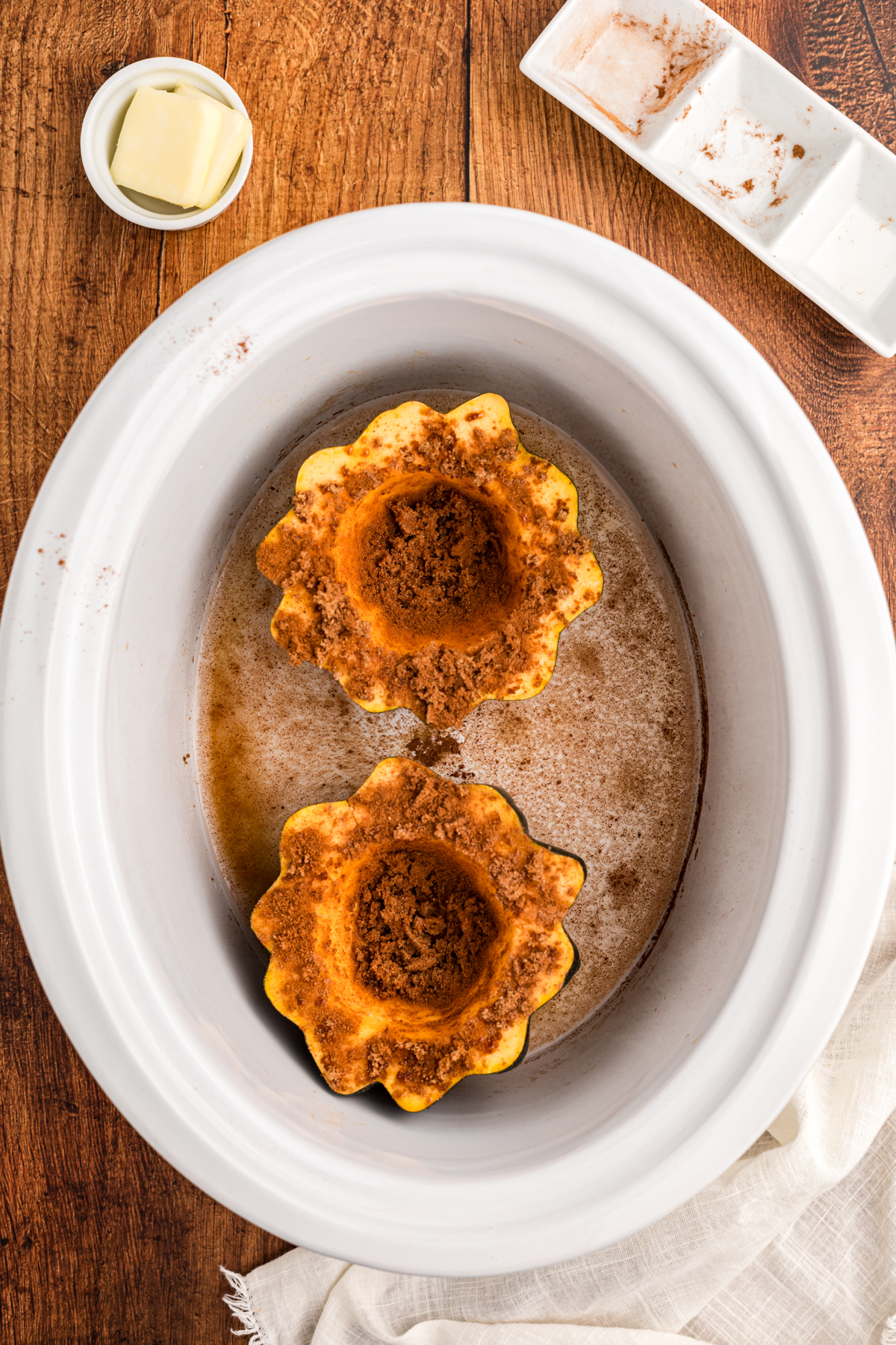 acorn squash in a slow cooker with water, cinnamon, nutmeg, and brown sugar.