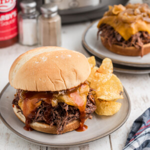 two plated slow cooker arby's beef and cheddar sandwiches.