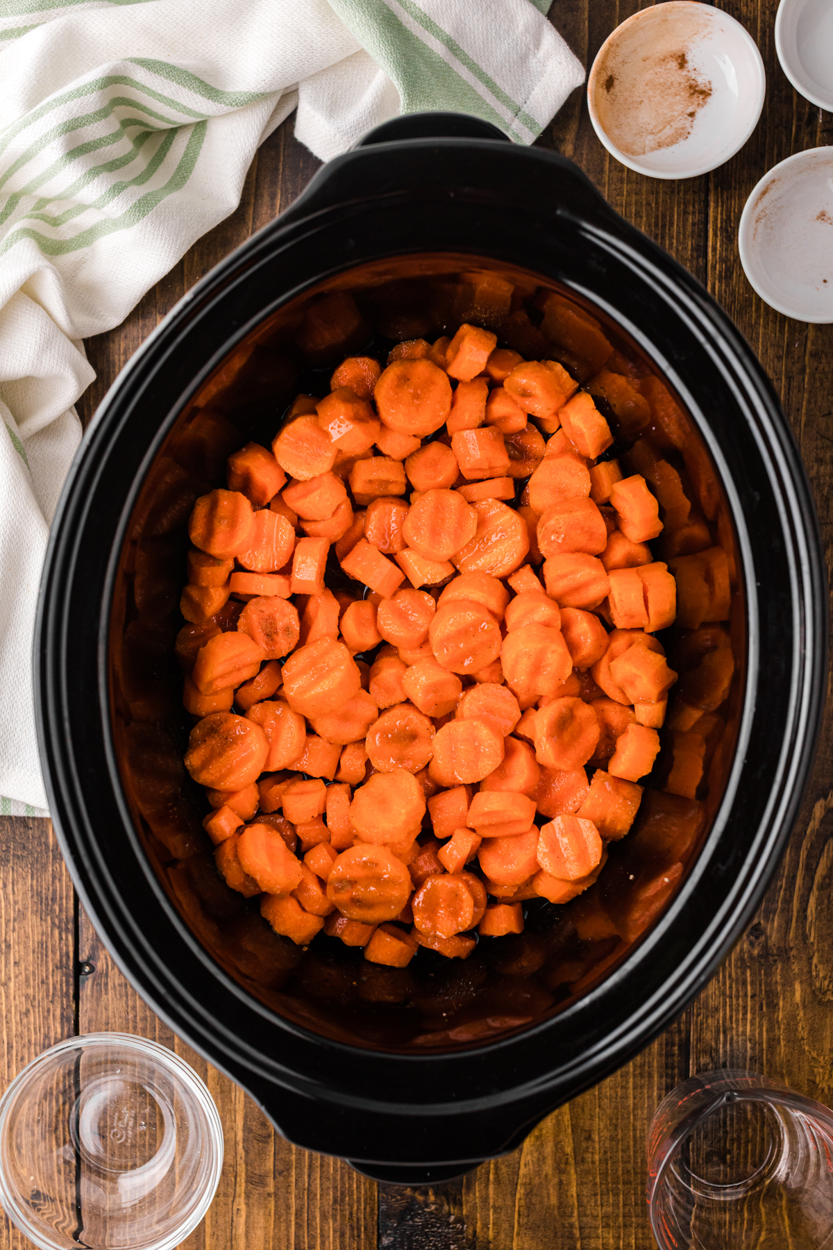 sliced carrots with seasonings and water stirred together in a slow cooker.