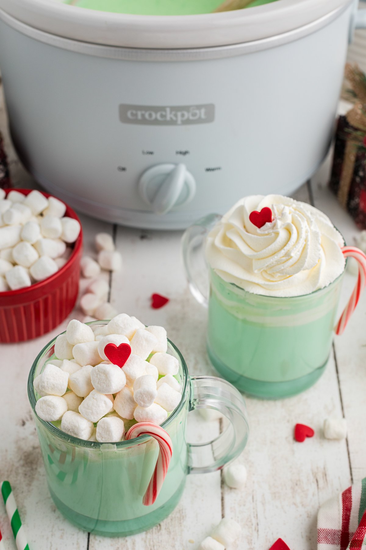 Two clear mugs of slow cooker grinch hot chocolate.