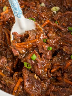 overhead of slow cooker mongolian beef with a spoon scooping some out.