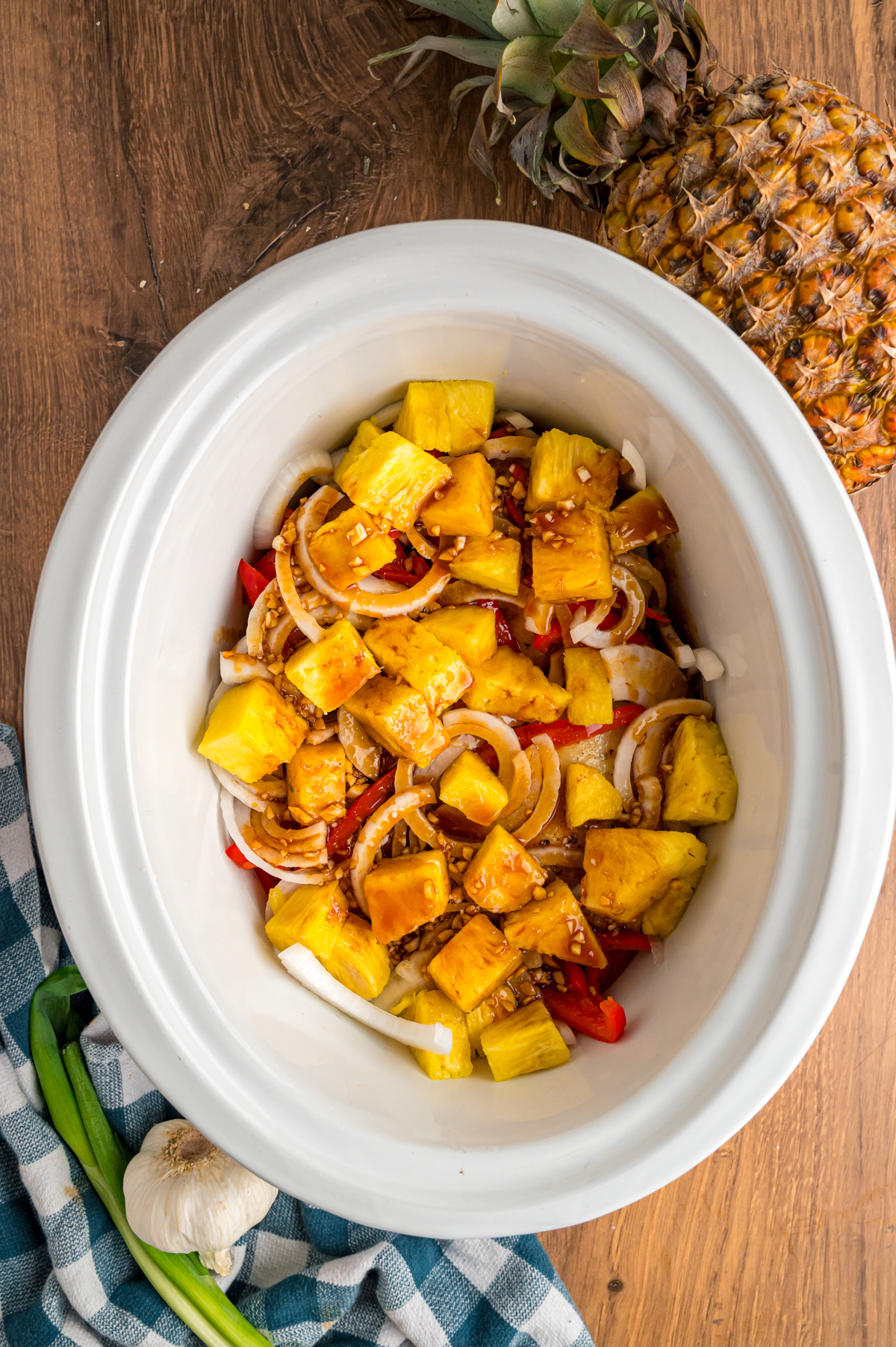 seared chicken thighs topped with rest of ingredients in a slow cooker before cooking.