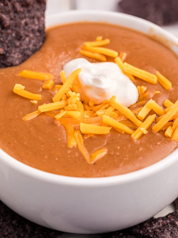 close-up of serving slow cooker refried bean soup in a bowl with cheese and sour cream.